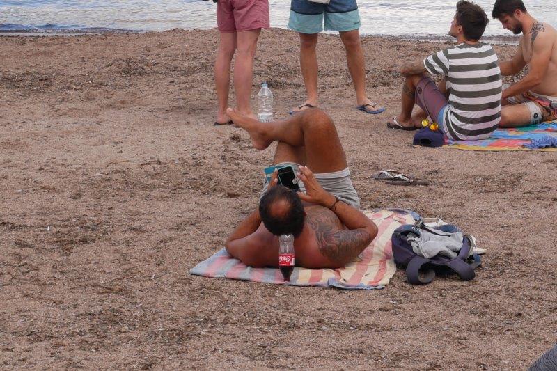 guy on the beach with a Coke bottle for a pillow